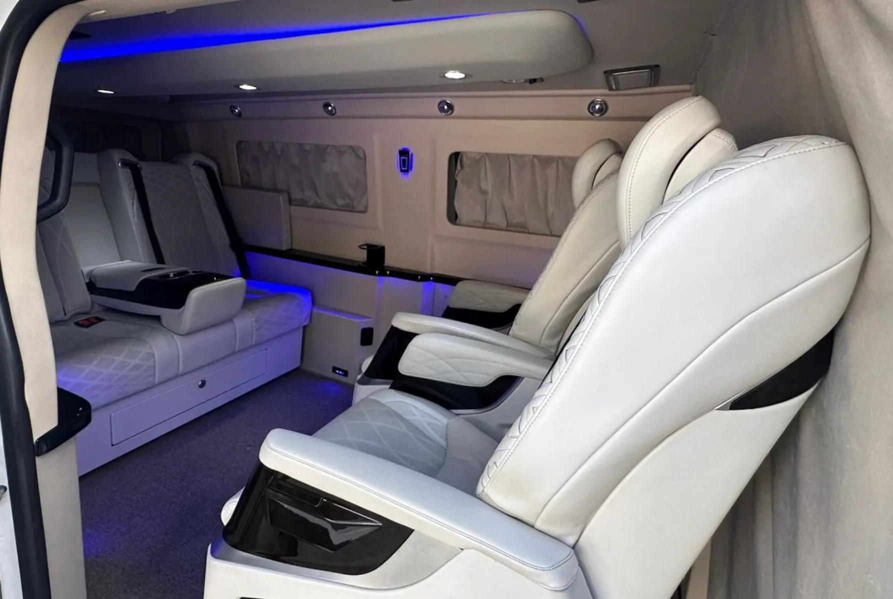 Interior premium da van com poltronas brancas e iluminação ambiente