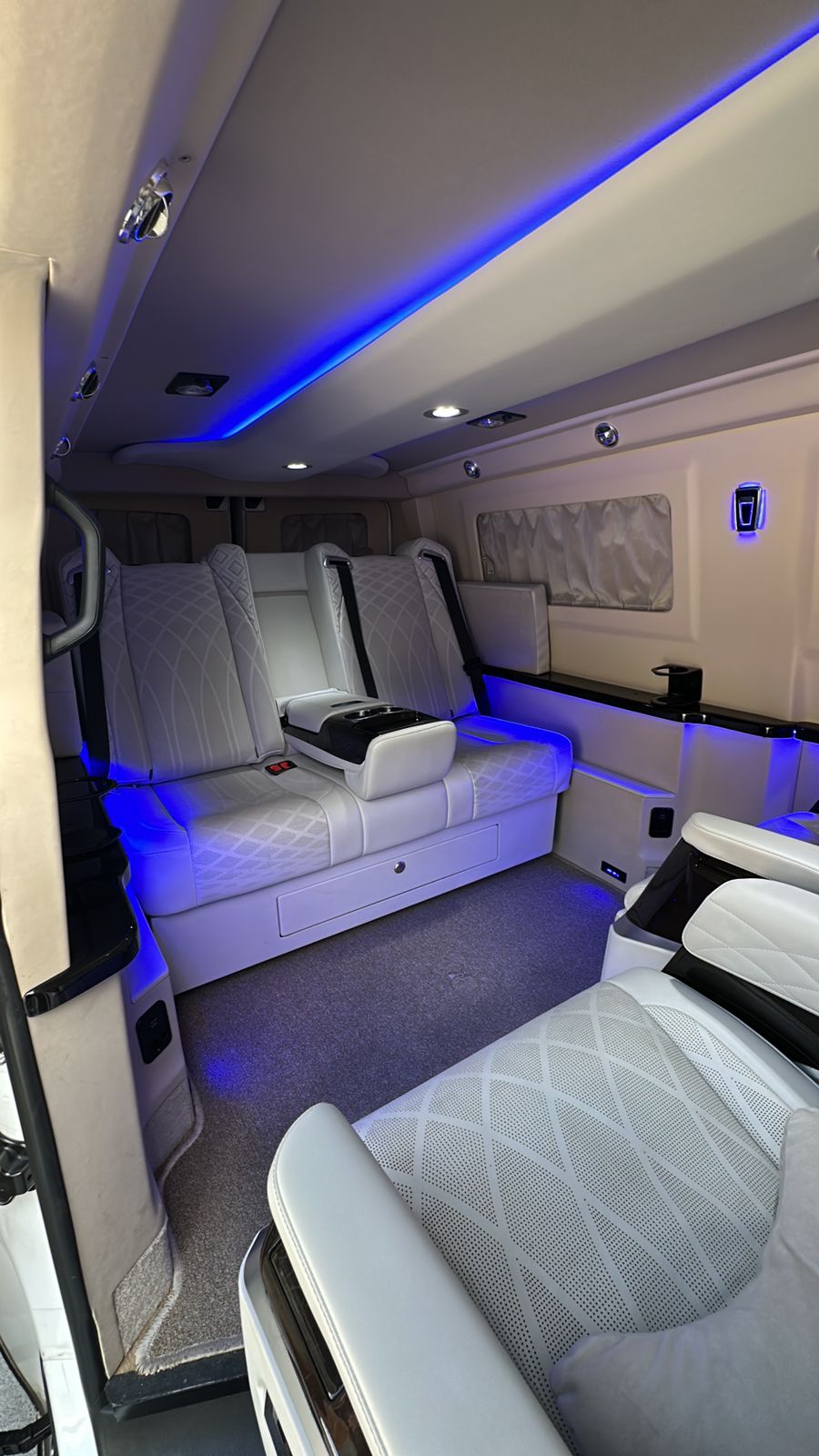 Interior da mini van executiva com iluminação ambiente e poltronas de luxo